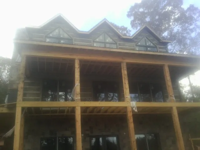 Dormers and porch framing on a large log home under construction — Roof Coating work by our crew in Belmont